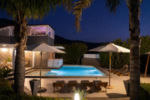 a swimming pool with two umbrellas and a house at Moresca Luxury Private Villa & Spa in Castellammare del Golfo +107 photos