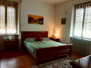 a bedroom with a bed with a green comforter and two windows at Appartamento luna, vicino centro storico in Spilimbergo