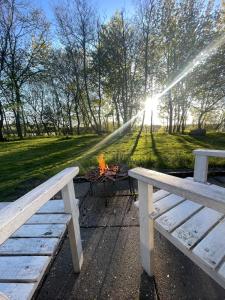 two benches sitting next to a picnic table with a fire at La Petite Ecole in Bindslev