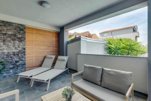 two chairs and a couch on a balcony at Apartmani Pocco Locco in Biograd na Moru
