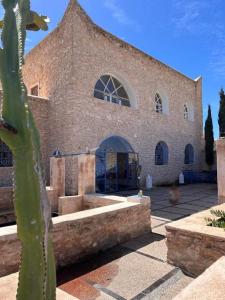 a large brick building with a cactus in front of it at Dar Joud Kaouki in Sidi Kaouki