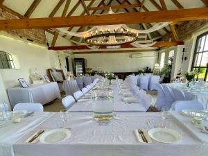 a long dining room with white tables and white chairs at Wingårdhs B&B Österlen in Löderup
