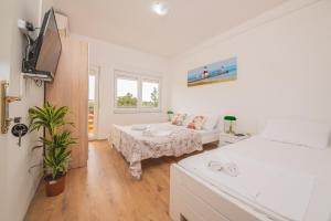 a white bedroom with a bed and a table at Hotel Riviera in Starigrad