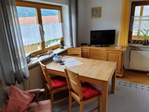 a kitchen with a wooden table and chairs and a television at Ferienwohnung Renate in Siegsdorf