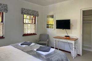 a bedroom with a bed and a desk and a television at Chinta Cottage Hermanus in Hermanus