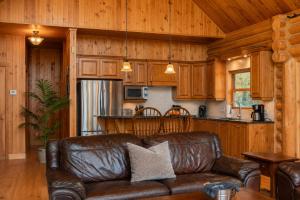 a leather couch in a living room with a kitchen at Fiddler Lake Resort - Deer 90 in Mille-Isles