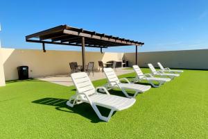 a row of white chairs sitting on the grass at Beautiful apartment just 1 block from the beach. in Mazatlán