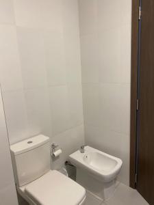 a white bathroom with a toilet and a sink at Monoambiente Cipolletti in Cipolletti