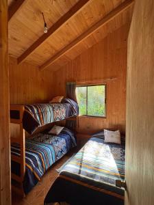 two bunk beds in a cabin with a window at Parcela Peumayen casa 2 in Pucura