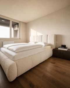 a large white bed in a room with wooden floors at The Loft, An Architects Dream in Târgu-Mureş