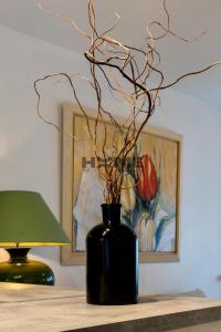 a black vase on a table with a lamp and a painting at Family House in Caudry