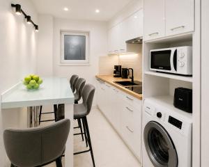 a white kitchen with a table and a microwave at Metropole Apartments Romana Square in Bucharest +10 photos