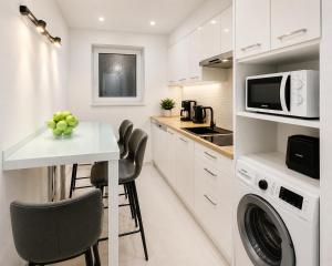 a white kitchen with a table and a microwave at Metropole Apartments Romana Square in Bucharest