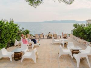 a group of people sitting on a patio near the water at Rosys Little Village in Skala