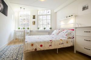 a white bedroom with a bed and a desk at Spui's the Limit in Amsterdam