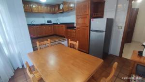 a kitchen with a wooden table and a refrigerator at Piso casco antiguo in Cedeira