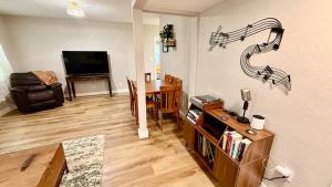 a living room with a television and a table with a music notes wall at Charming Citrus in Inverness