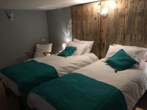 two beds in a hotel room with green pillows at Le Marancènes in Laroque-Timbaut