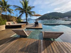a pool with two chairs and a table and water at Pousada e Mergulho Jamanta in Angra dos Reis
