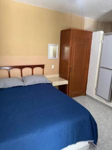 a bedroom with a blue bed and a wooden cabinet at Hotel Los Arcos in Pénjamo
