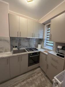 a kitchen with white cabinets and a sink at Sofia Apartment in Galaţi +12 photos