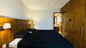 a bedroom with a large black bed and a cabinet at Promoção - Flat em Brasília in Brasília +5 photos