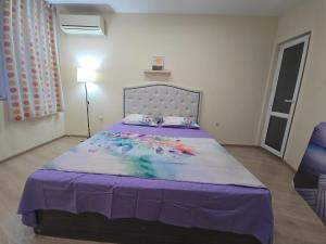 a bedroom with a large bed with a purple blanket at Grand and Prime Central Apartments Varna in Varna City