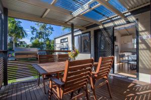 a patio with a wooden table and chairs on a deck at The Mook Mollymook in Mollymook
