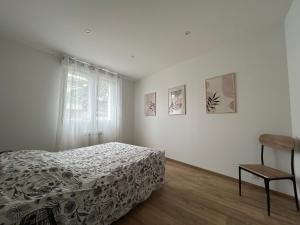 a bedroom with a bed and a window and a chair at Le Cosy in Saint-Marcellin