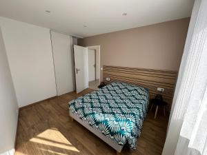 a bedroom with a bed and a wooden floor at Le Cosy in Saint-Marcellin