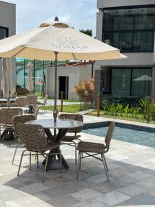 a table and chairs with an umbrella next to a pool at Nomar 208 pe na areia na Praia dos carneiros in Tamandaré