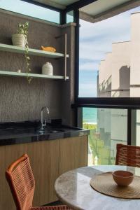 a kitchen with a sink and a table and a window at Nomar 208 pe na areia na Praia dos carneiros in Tamandaré