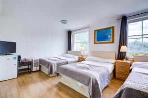 a hotel room with three beds and a television at Boltons Residence Collection Hotel London in London