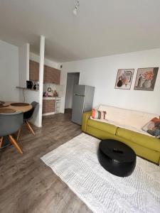 a living room with a yellow couch and a kitchen at La Parenthèse Calme in Tours
