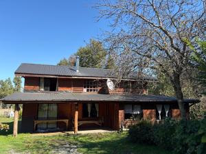a house with a black roof and a tree at Parcela Peumayen casa 3 in Pucura