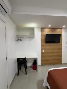 a bedroom with a desk and a tv on a wall at Priamo Hotel in Santo Antonio do Sudoeste