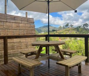 a picnic table with an umbrella and benches on a deck at Bosque Encantado Cabañas chalet in Guatapé