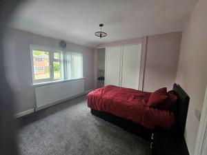 a bedroom with a red bed and a window at Elim House in Birmingham +2 photos