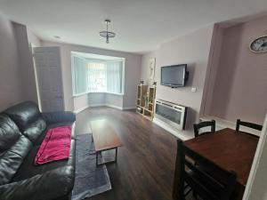 a living room with a black leather couch and a table at Elim House in Birmingham