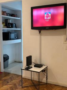 a flat screen tv hanging on a wall with a table at RECOLETA APART in Buenos Aires