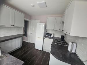 a kitchen with white appliances and wooden floors at Elim House in Birmingham