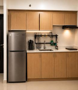 a kitchen with a stainless steel refrigerator and wooden cabinets at Davao City Stay at Camella Northpoint Spacious 3BR Condo 5Beds Up to 10 Guests in Davao City