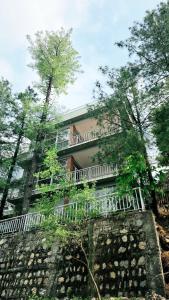 a building with a fence and trees in front of it at Nathia Lodge Cottage in Nathia Gali