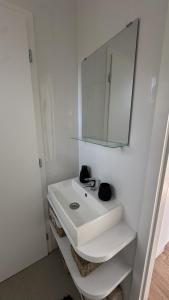 a white bathroom with a sink and a mirror at EkoHniezdo Slovenský Raj in Smižany