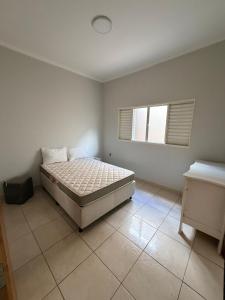 a white bedroom with a bed and a window at Casa Cambuí Molina in Franca