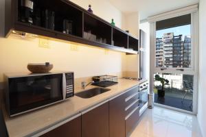 a kitchen with a microwave and a sink and a window at SkyPort Olivos Vista al Río, Rooftop y Piscina Cubierta in Olivos