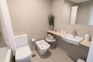 a white bathroom with a toilet and a sink at SkyPort Olivos Vista al Río, Rooftop y Piscina Cubierta in Olivos