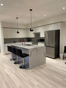 a kitchen with a large kitchen island with black chairs at Luxury EW Bed & Breakfast in Abbotsford