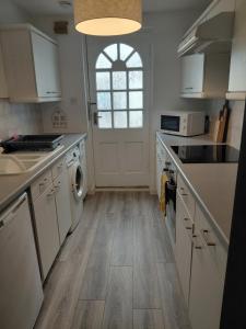 a kitchen with white cabinets and a white door at Little Nuek in Largs