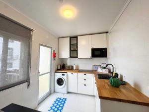 a kitchen with white cabinets and a washer and dryer at Horta Joy! in Horta